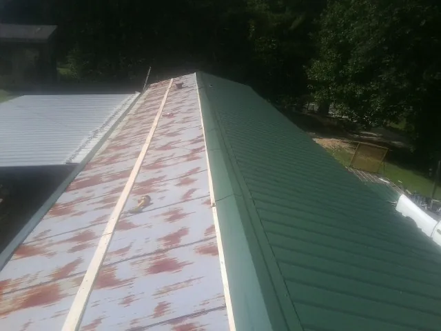 Old rusted panels beside newly installed green metal roofing — Wind Damage Roof Repair by Roofing Brothers in Dearborn Heights