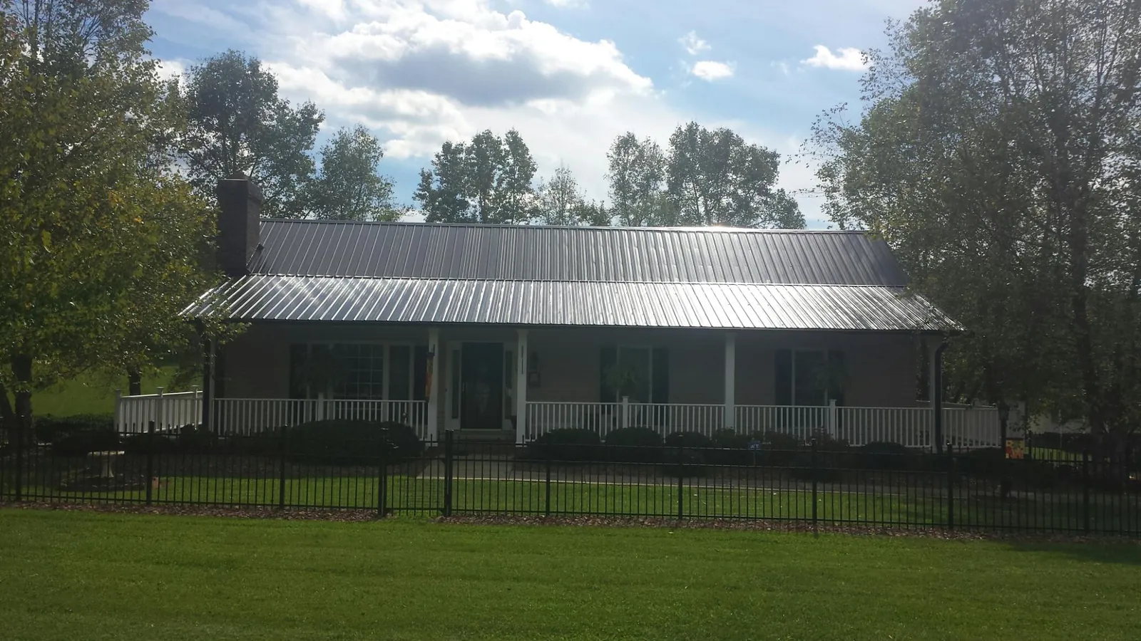 Gray metal roof on a brick ranch with a full width front porch — Gutter Guard Installation work by our crew in Dearborn Heights