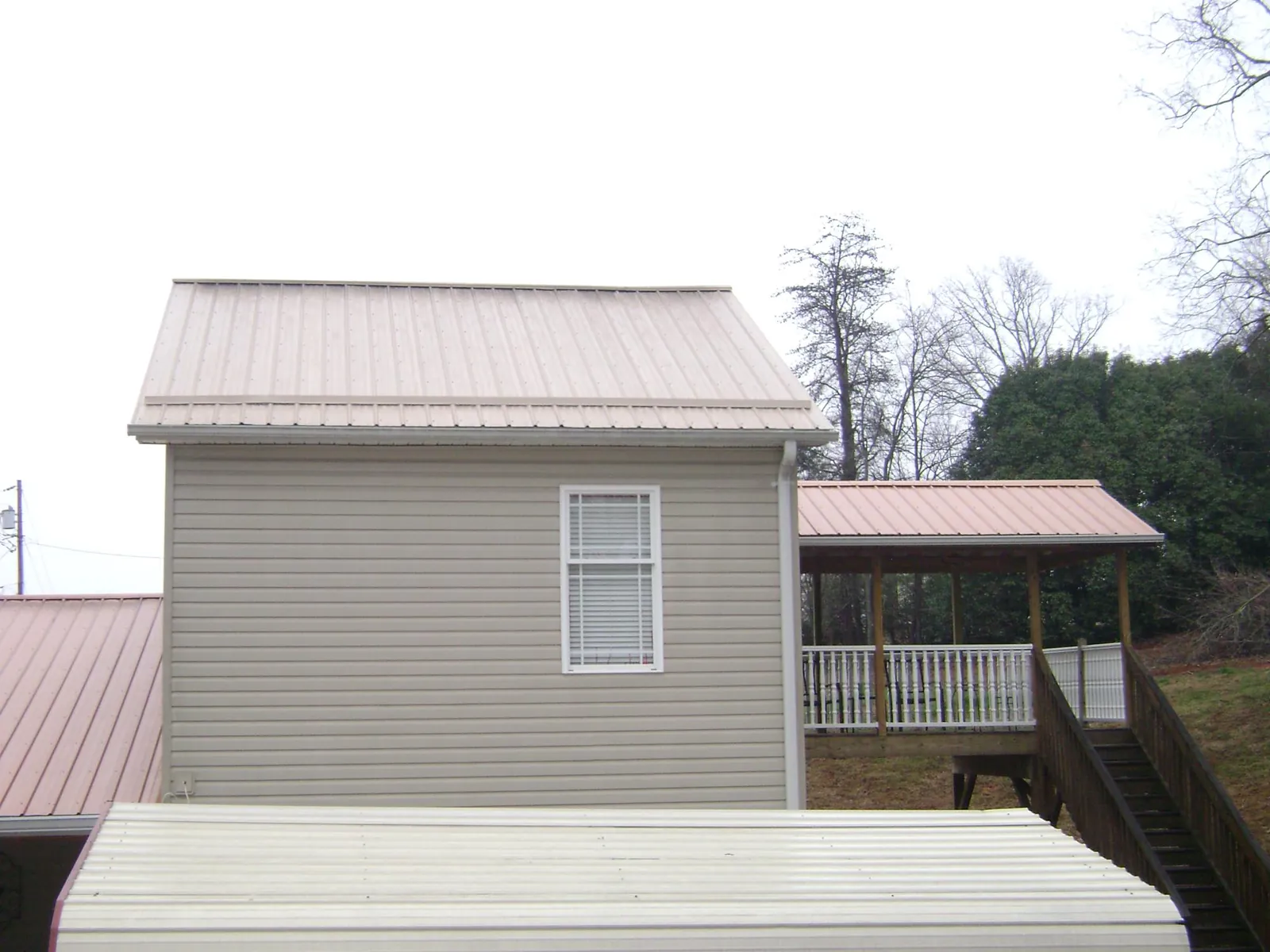 Tan metal roofs on a two story addition and attached porch, from a Roof Replacement job in Dearborn Heights
