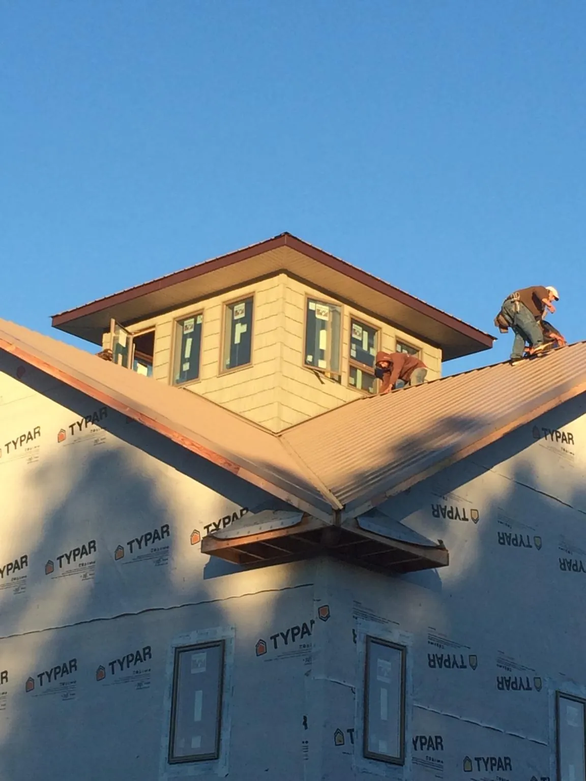 Roofers working around a rooftop cupola on a new metal roof at sunset — Roof Waterproofing in Dearborn Heights by Roofing Brothers